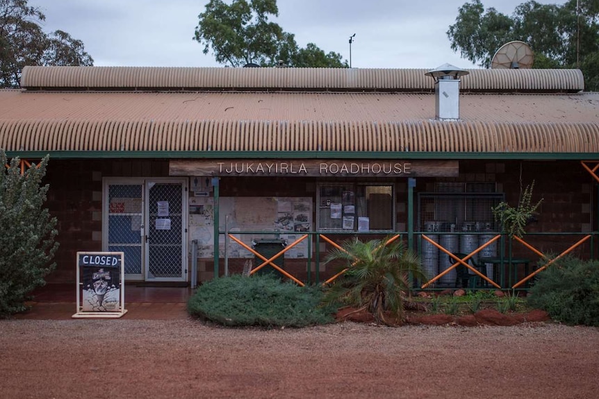 A roadhouse surrounded by trees, with a sign that says 'Tjukayirla Roadhouse'