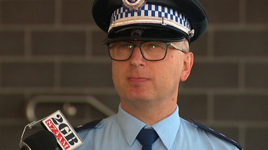 A police officer stands in front of a media microphone