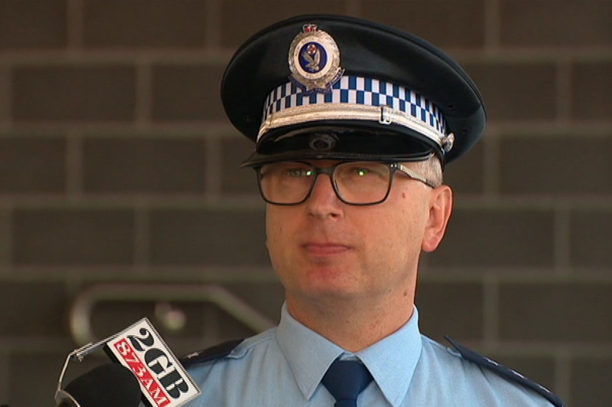 A police officer stands in front of a media microphone