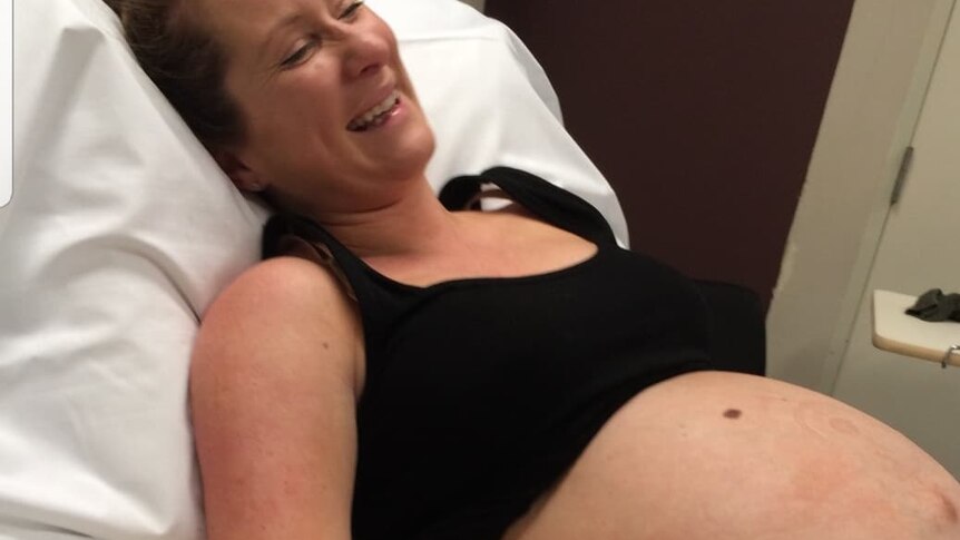 Exposed pregnant belly of woman in hospital bed not long before birthing