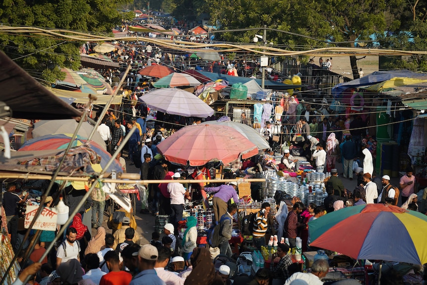 A shot from above shows crowds of people at a colourful market