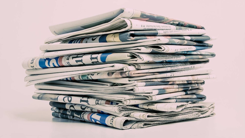 A collection of newspapers in a stack on top of each other.