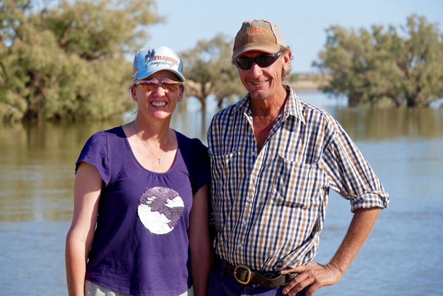 Graziers Fiona Lander and Geoff Davies pose in front of paddocks flooded. 