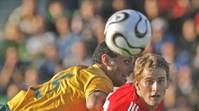 Australian forward John Aloisi attempts to head the ball past a Liechtenstein defender.