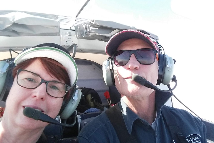 A woman and a man in the cockpit of a small plane.