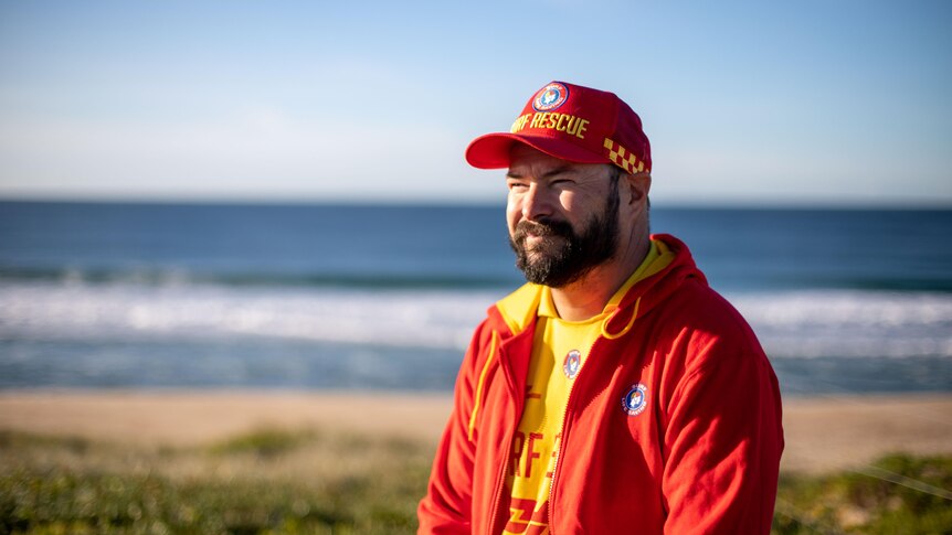 NSW Central Coast Surf Lifesaver Patrick Jacob wearing red jacket and red cap on the beach
