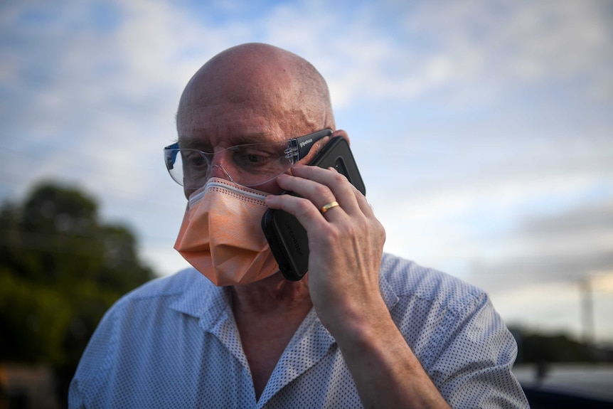 Nurse Shane Durance in protective gear talking on a mobile phone