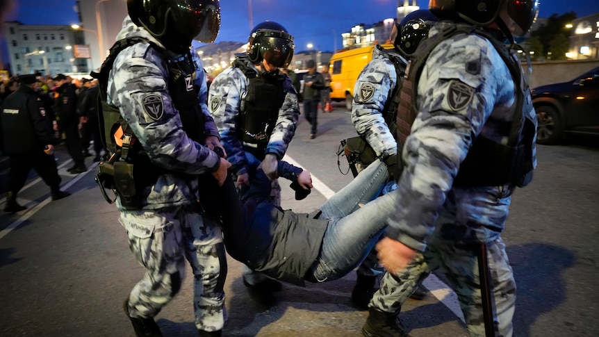 Four riot police members carry a protester during anti-war demonstrations in Moscow.
