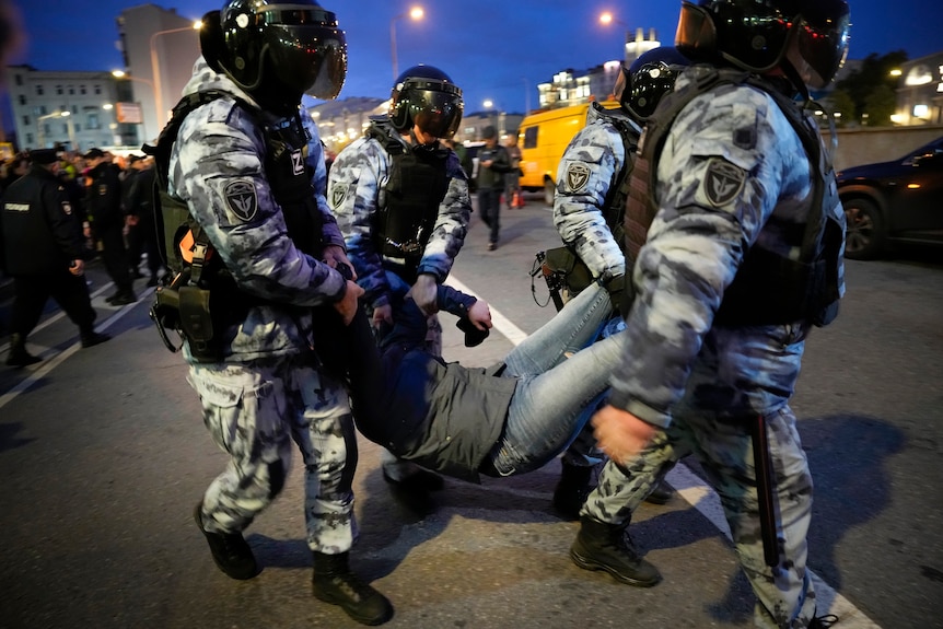 Cuatro policías antidisturbios llevan a un manifestante durante las manifestaciones contra la guerra en Moscú.