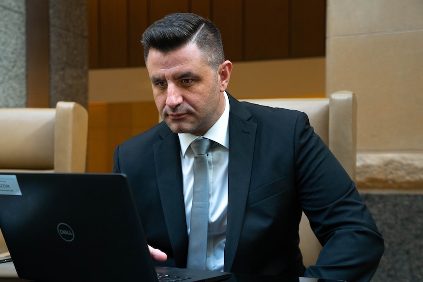 a man in a suit looking at a laptop intensely