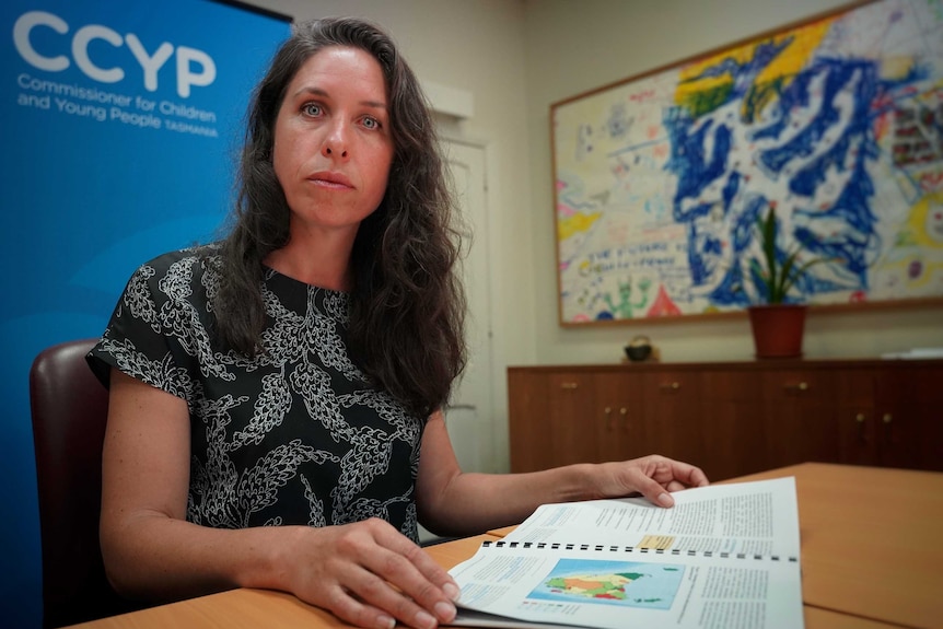 Commissioner for Children and Young People Leanne McLean sits at a desk with a report in her hands.