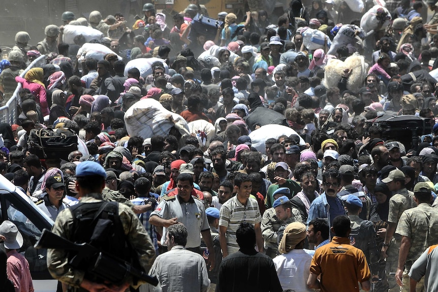 Syrian refugees wait for transportation after crossing into Turkey