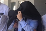 Massage therapist Marcello Scariati, handcuffed and with a jacket over his head, is escorted from a Perth court.