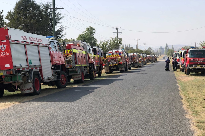 Red fire trucks lines a country road.