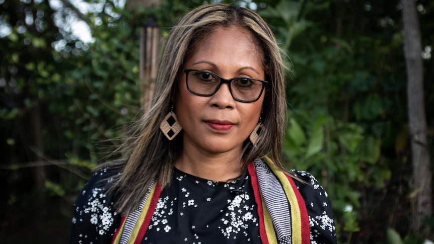 Portrait of a woman with colourful scarf standing outside.