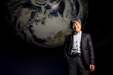 Professor Shin-Chan Han stands in front of a large globe.