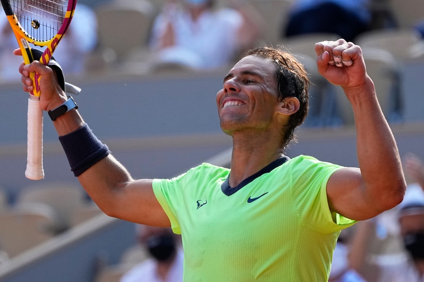 A grinning Rafael Nadal pumps his fists and brandishes his racquet in one hand after a match.