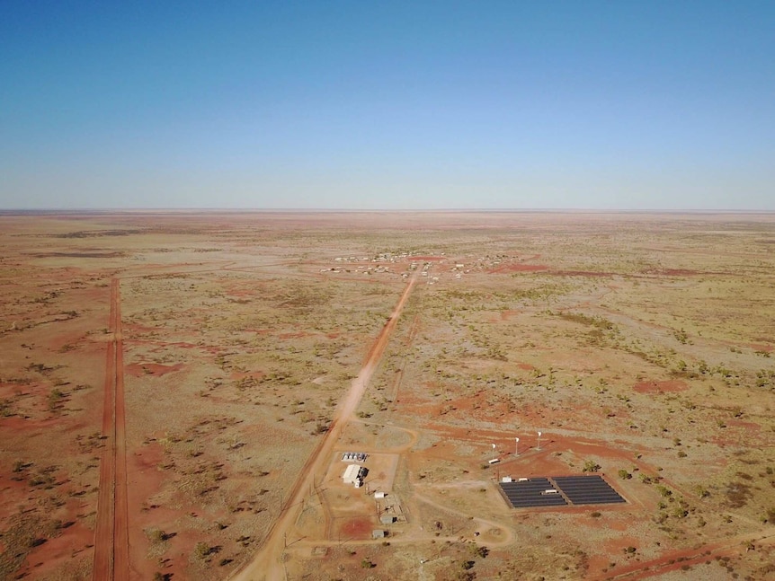 A wide drone shot of the solar farm with the community in the distance.