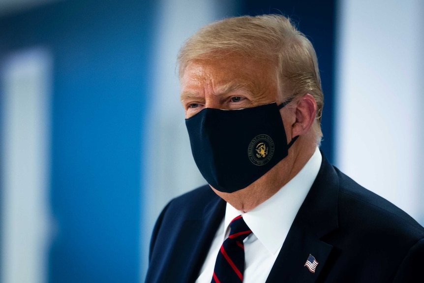President Donald Trump wears a face mask as he tours the American Red Cross national headquarters.