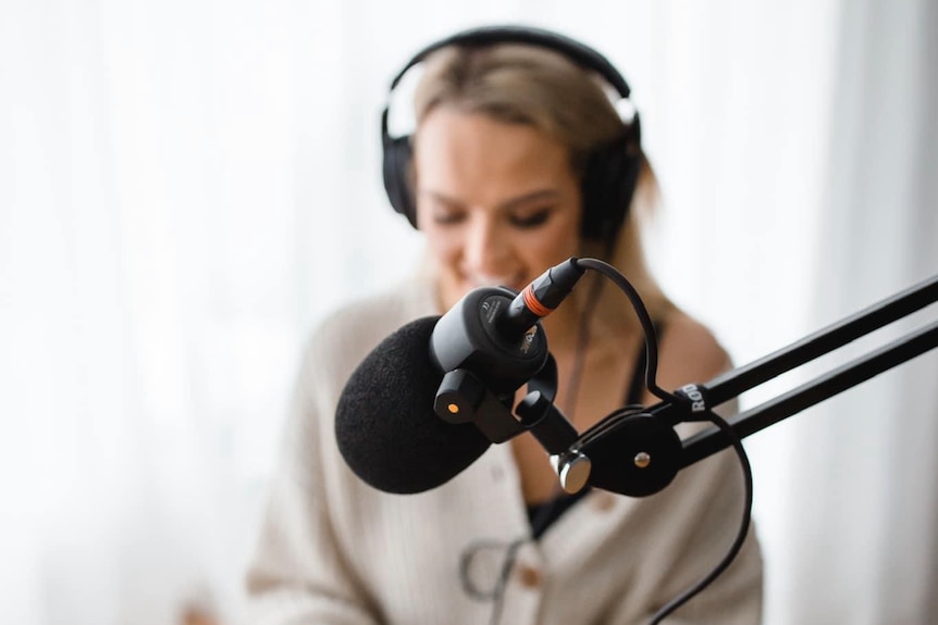 woman with blonde hair talking into microphone