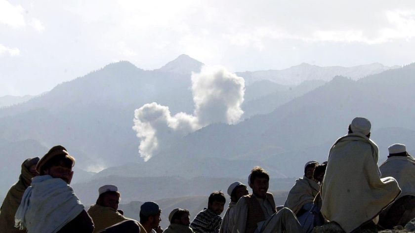 Afghan villagers watch as smoke from bombs dropped by US planes rises from Al Qaeda positions in December 2001.