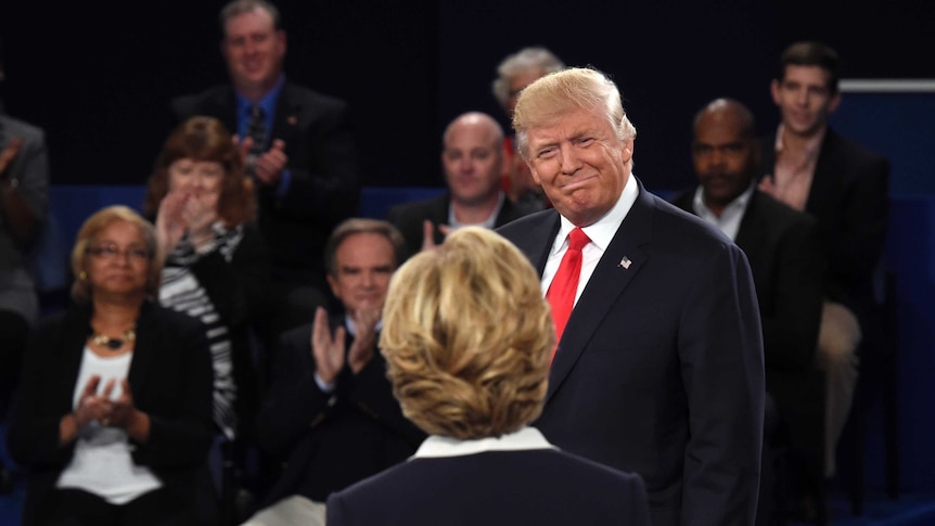 Donald Trump looks at Hilary Clinton with a smile before the debate