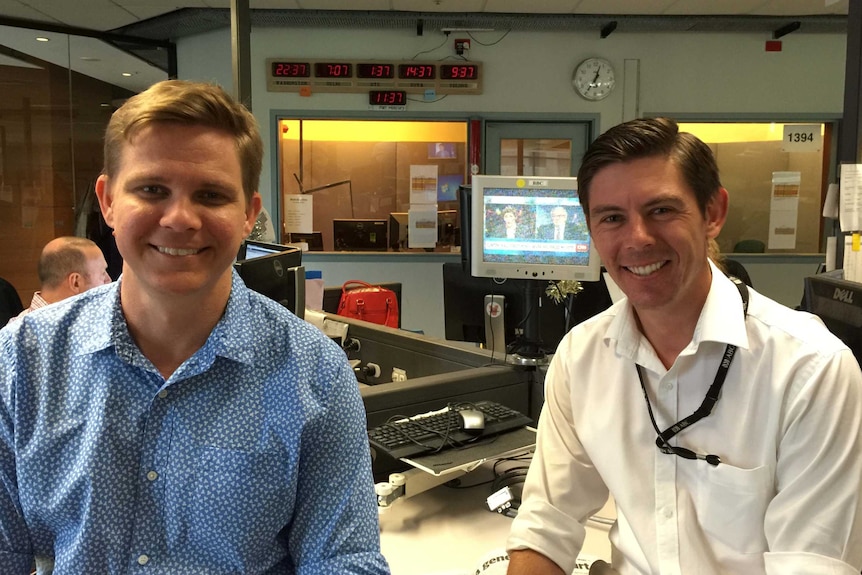 Liam Fox and Eric Tlozek in newsroom smiling to camera.