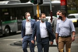 A line of men walking through Perth while wearing COVID masks