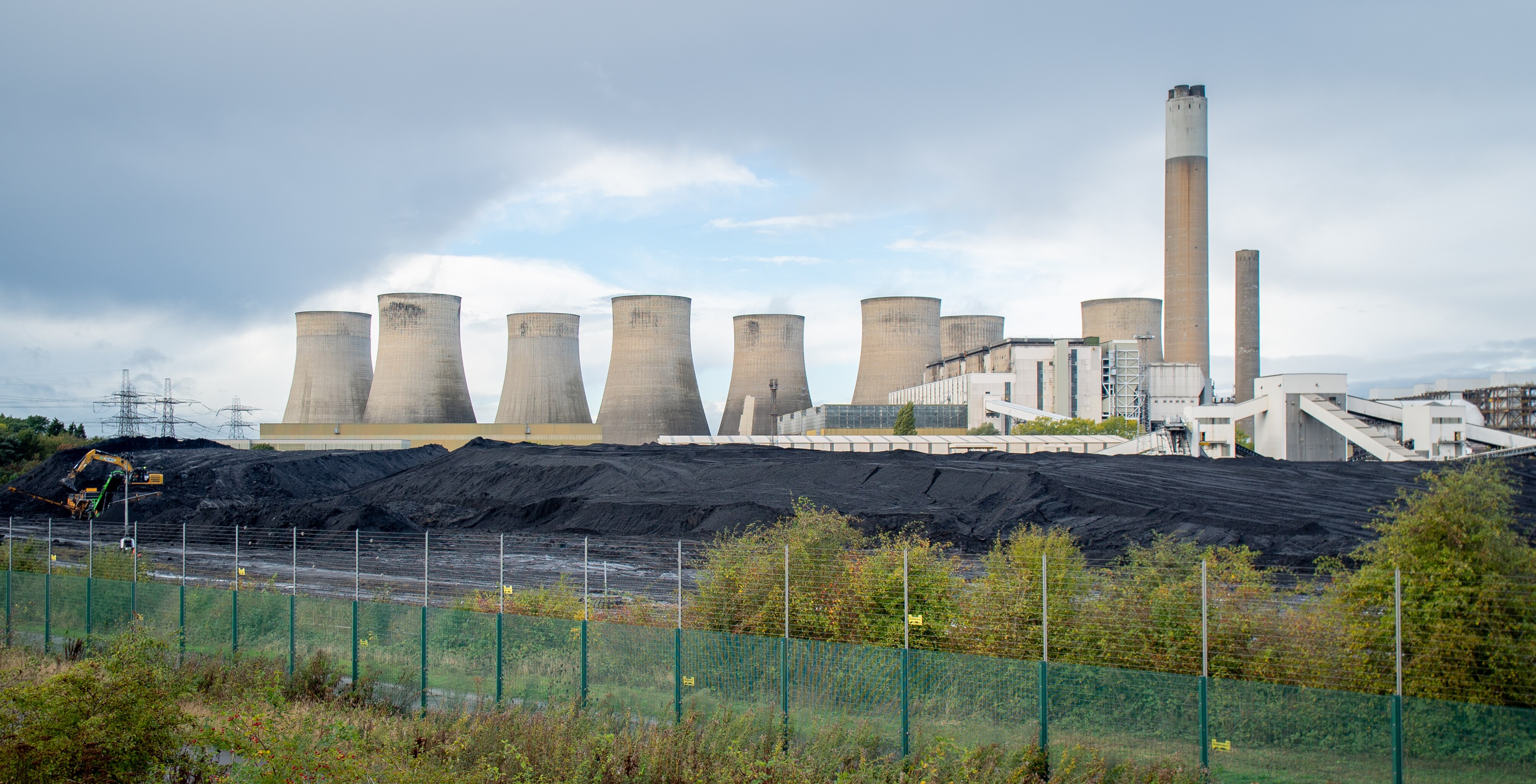 Mounds of coal sits in front of cooling stacks of a power station.