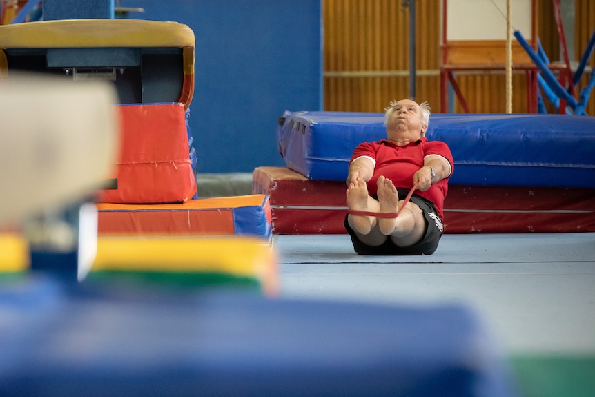 A man exercises on the ground at a colourful gym.