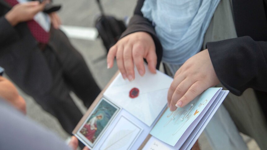 A woman's hands rest on a display book featuring condolence cards and messages for Aiia Maasarwe's loved ones.