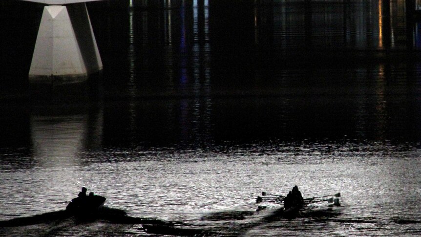 A rowing crew trains on the Brisbane River in the pre-dawn.