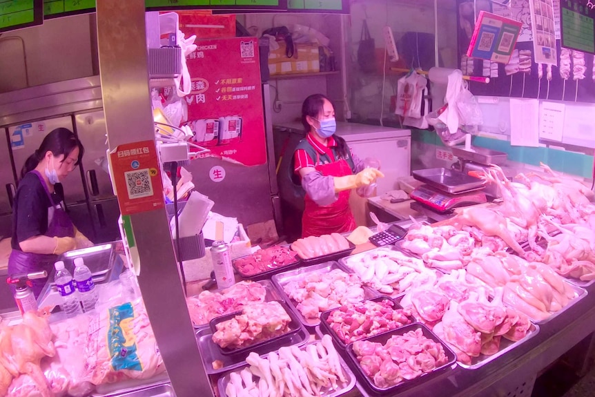 Two women in face masks behind a meat counter