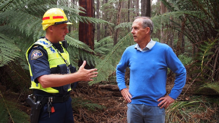 Bob Brown standing in a forest being told by a police officer he is about to be arrested.