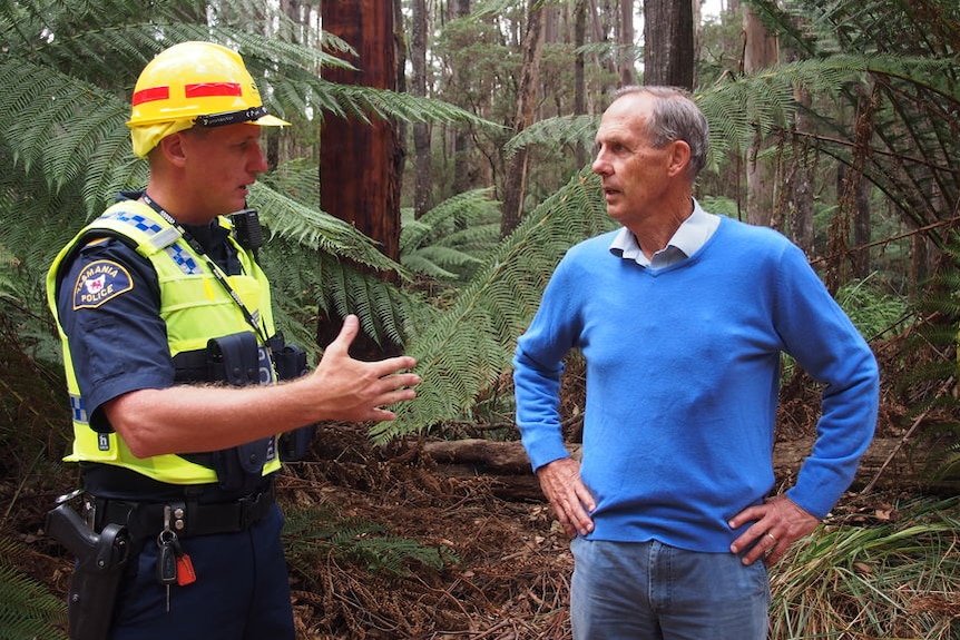 Bob Brown standing in a forest being told by a police officer he is about to be arrested.