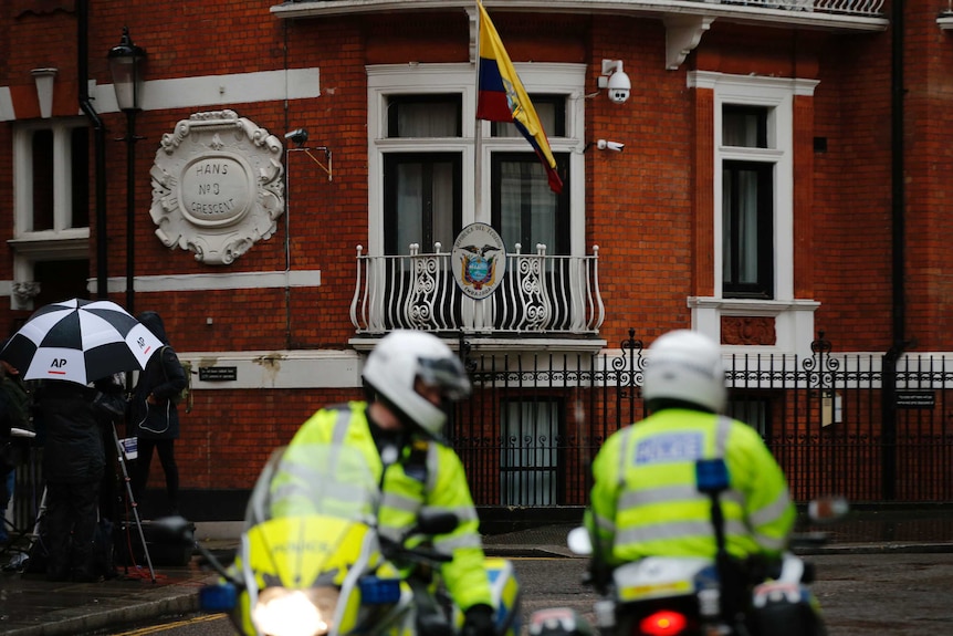 Police motorcyclists briefly stop outside the Ecuadorian embassy in London.
