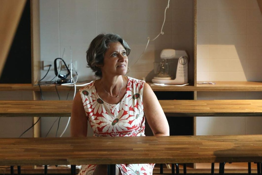 A woman sitting at a wooden table looking at a man who is sitting down.