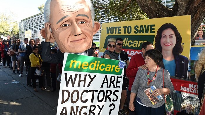 Photograph of protester wearing a Malcolm Turnbull mask and holding a placard that says Medicare: why are doctors angry?