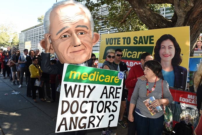 Photograph of protester wearing a Malcolm Turnbull mask and holding a placard that says Medicare: why are doctors angry?