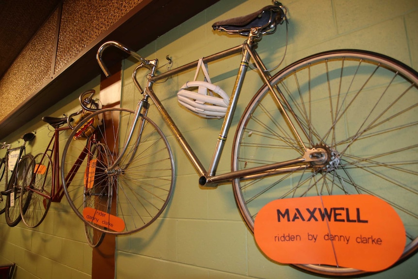 An old bike with big wheels handing on a green wall