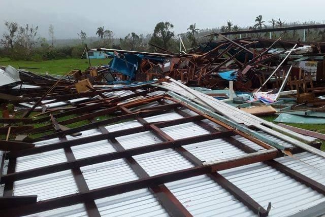 A house lay in ruins with sheets of tin and iron twisted on the ground.