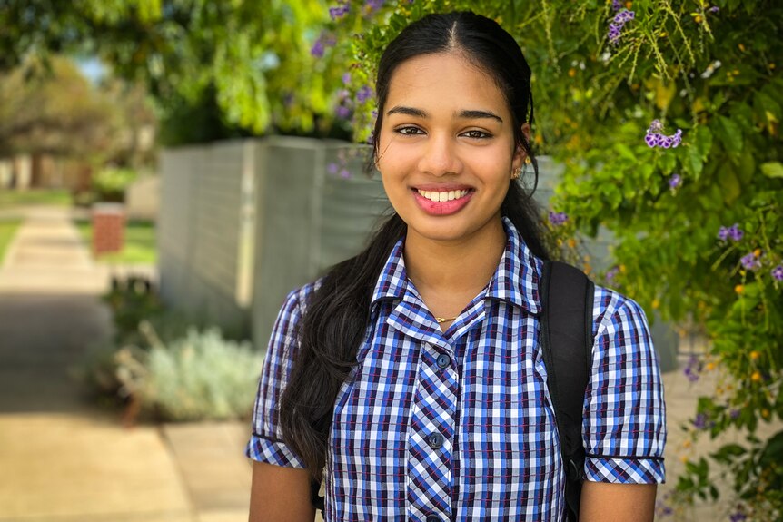 A young brown girl in school uniform wearing a big smile. She's happy in her skin.