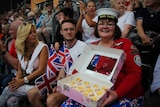 Kath Ryan sitting in crowd, showing off her vanilla butterfly cakes.