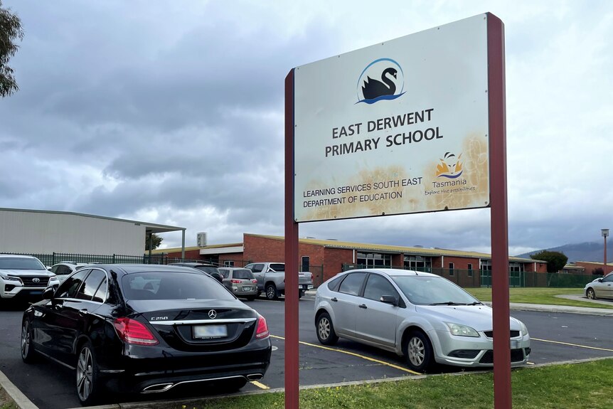 A school sign in the carpark outside school grounds.