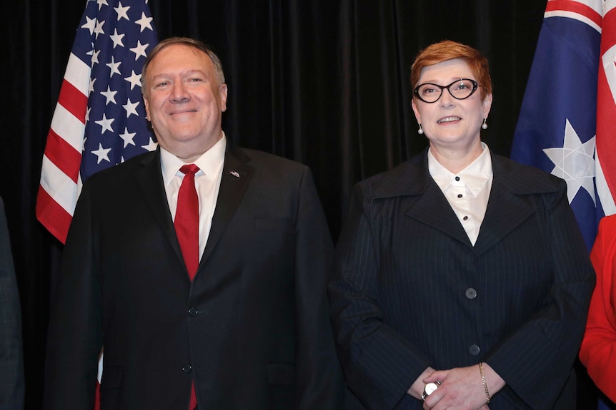 Mike Pompeo and Marise Payne stand in front of a black background and US and Australian flags.