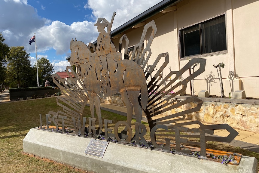 A metal sculpture of a soldier on a horse with the words 'Lest we forget'