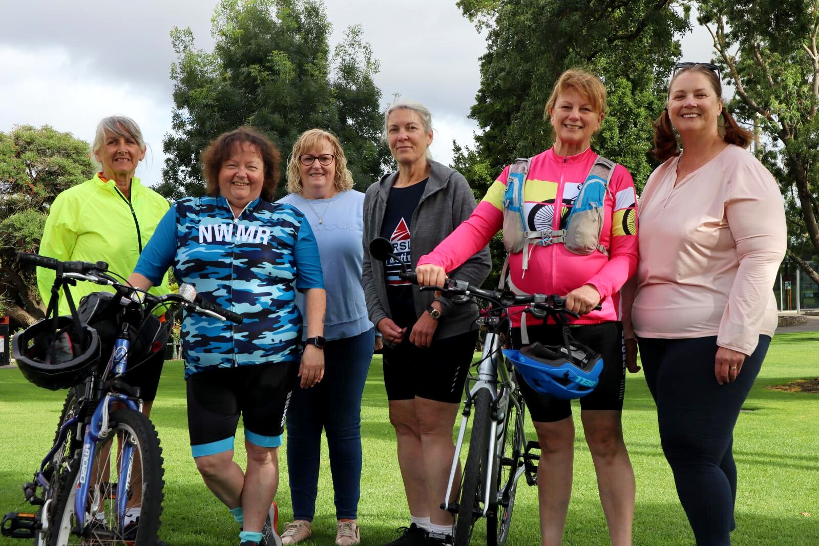 Six women standing with their bikes before going on a ride.
