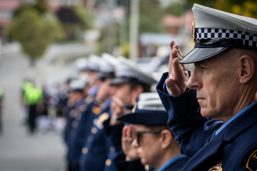 Tasmania Police officers saluting at a funeral procession for former officer.