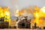An Israeli artillery unit fires toward targets in Gaza Strip in a burst of flames.