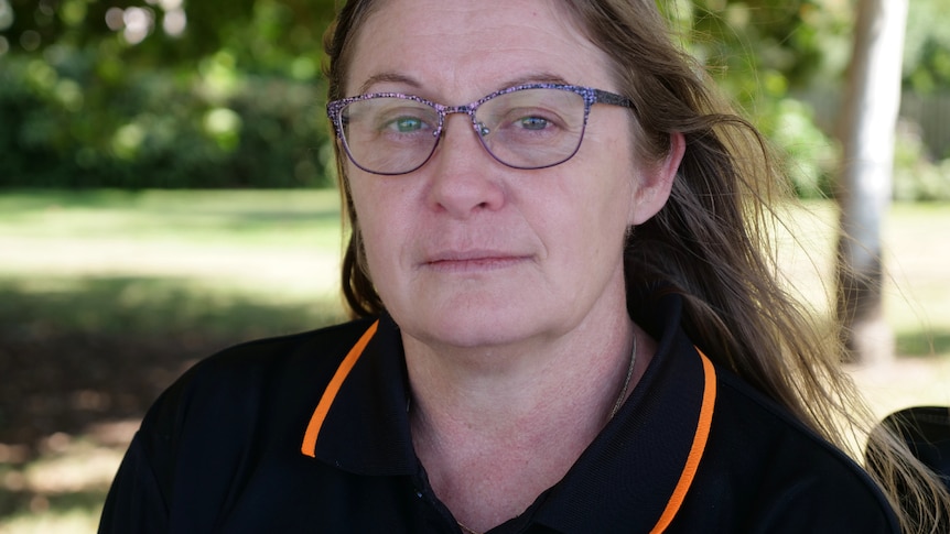 Close up of Kelli Downey, straight-faced, wearing glasses, hair out.